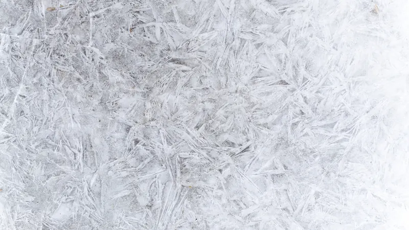 Ice crystals forming a frost pattern on a cold surface