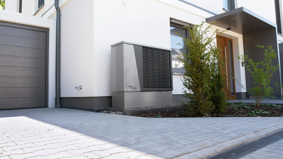 Air source heat pump outdoor unit beside the front of a modern house