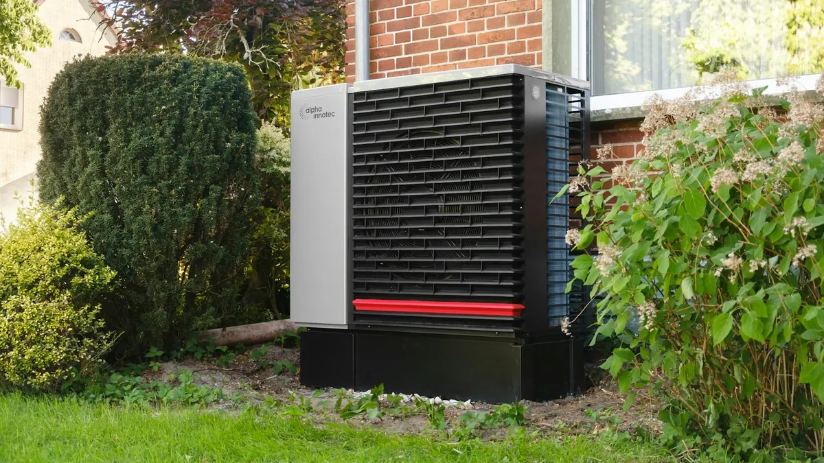 Air source heat pump in the garden of a brick house