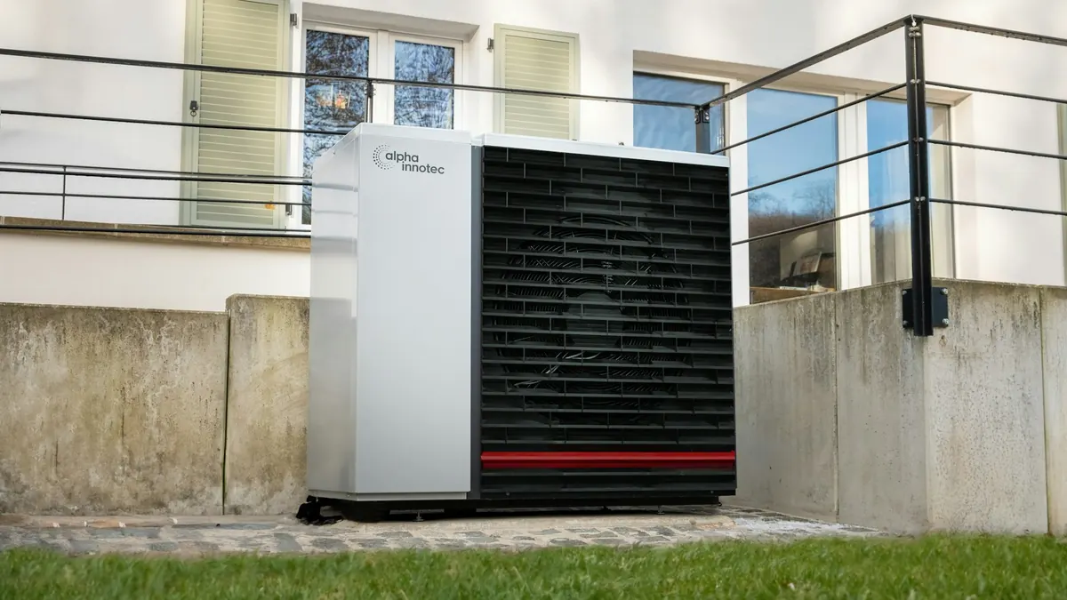 Air source heat pump on a lawn beside a house
