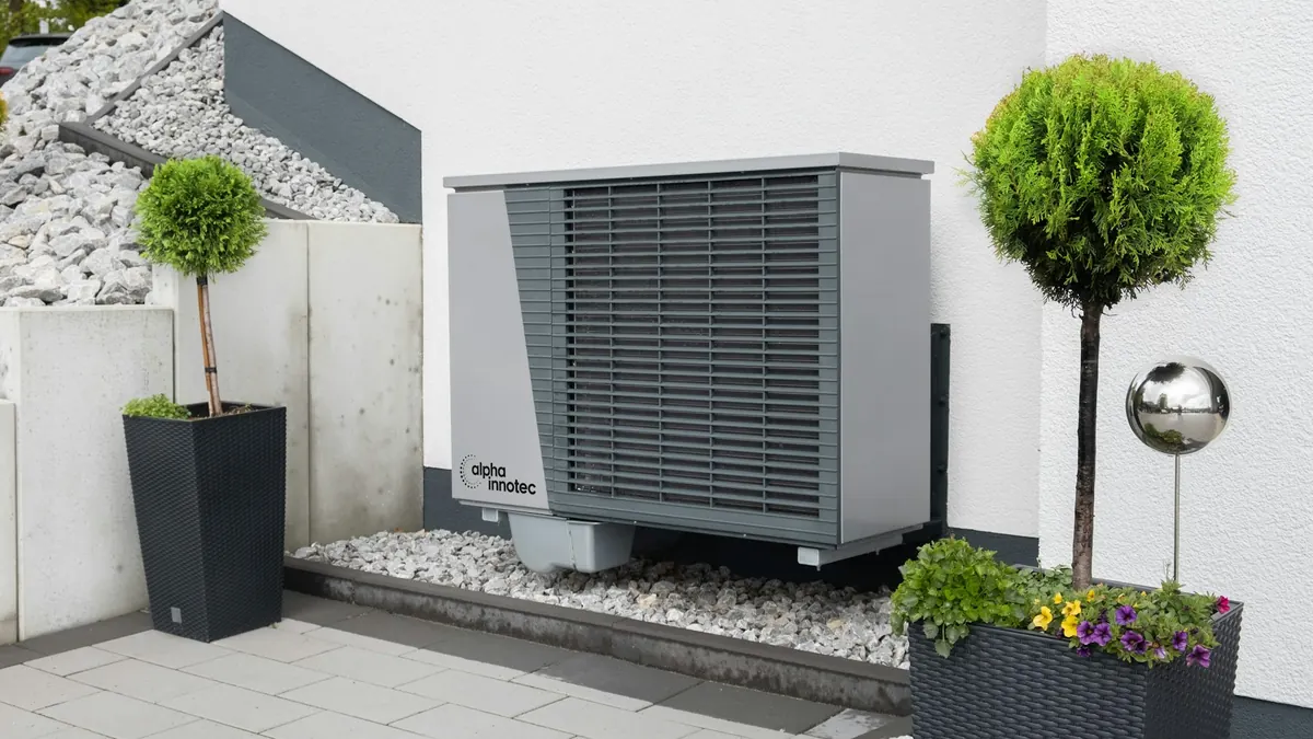 Heat pump outdoor unit on a paved patio with potted plants